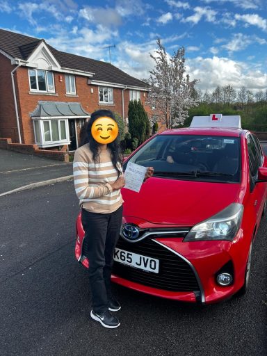 A person holding a clipboard stands next to a red car on a residential street.