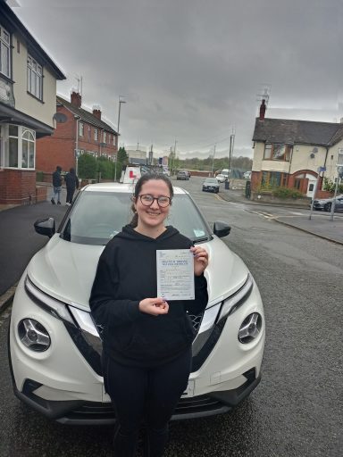 Person holding a certificate outside a car on a residential street.