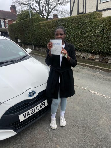 Person holding a document next to a white car parked on a residential street.