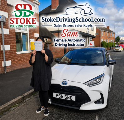 A woman holding a sign stands next to a white car outside a driving school.
