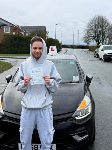 A person holding a driving test certificate in front of a black car.