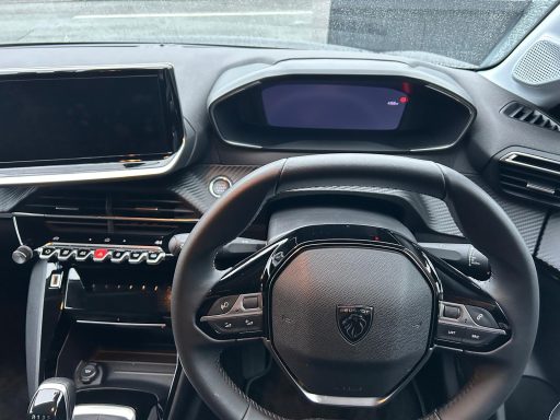 Interior view of a modern car dashboard featuring a steering wheel and two displays.