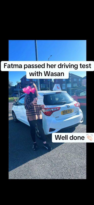 Fatima stands by a white car, celebrating after passing her driving test.