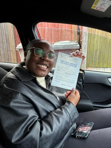 Smiling person holding a document while seated in a car.